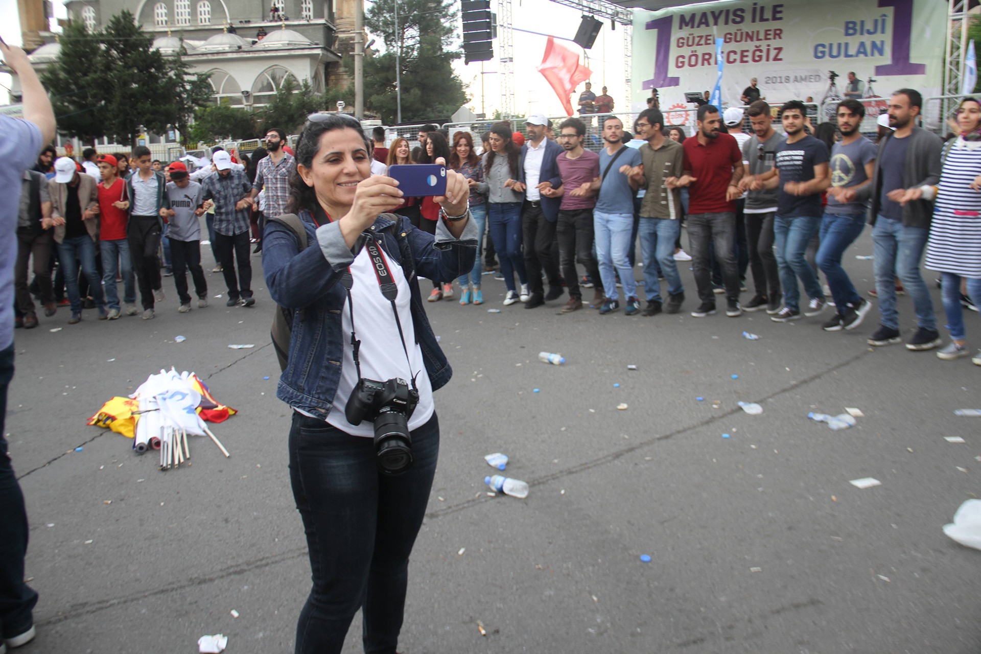 Kibriye Evren fotoğraf çekiyor, arkada halay çeken gençler var