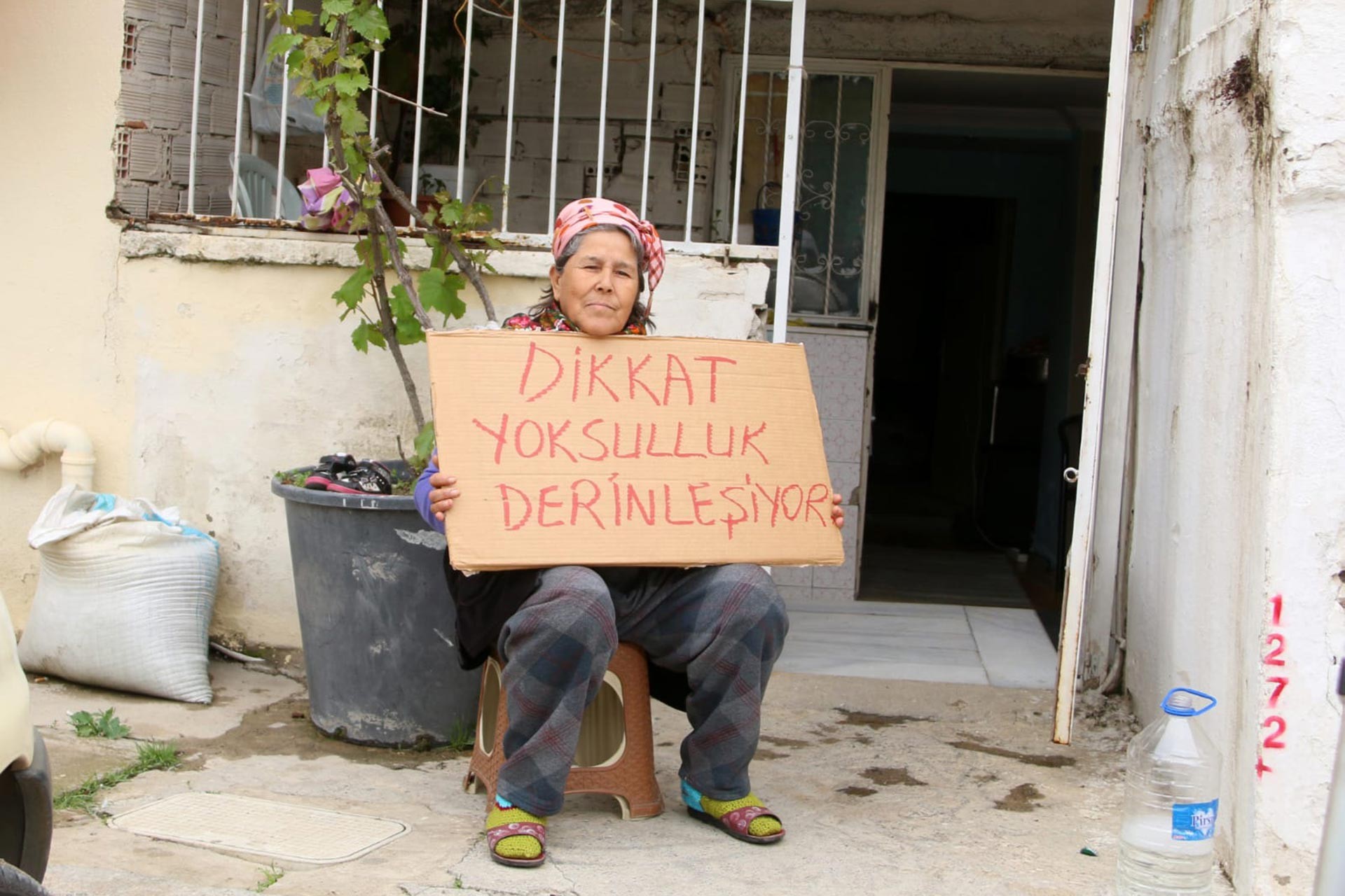 Dikkat yoksulluk derinleşiyor yazılı bir dövizi tutan kadın