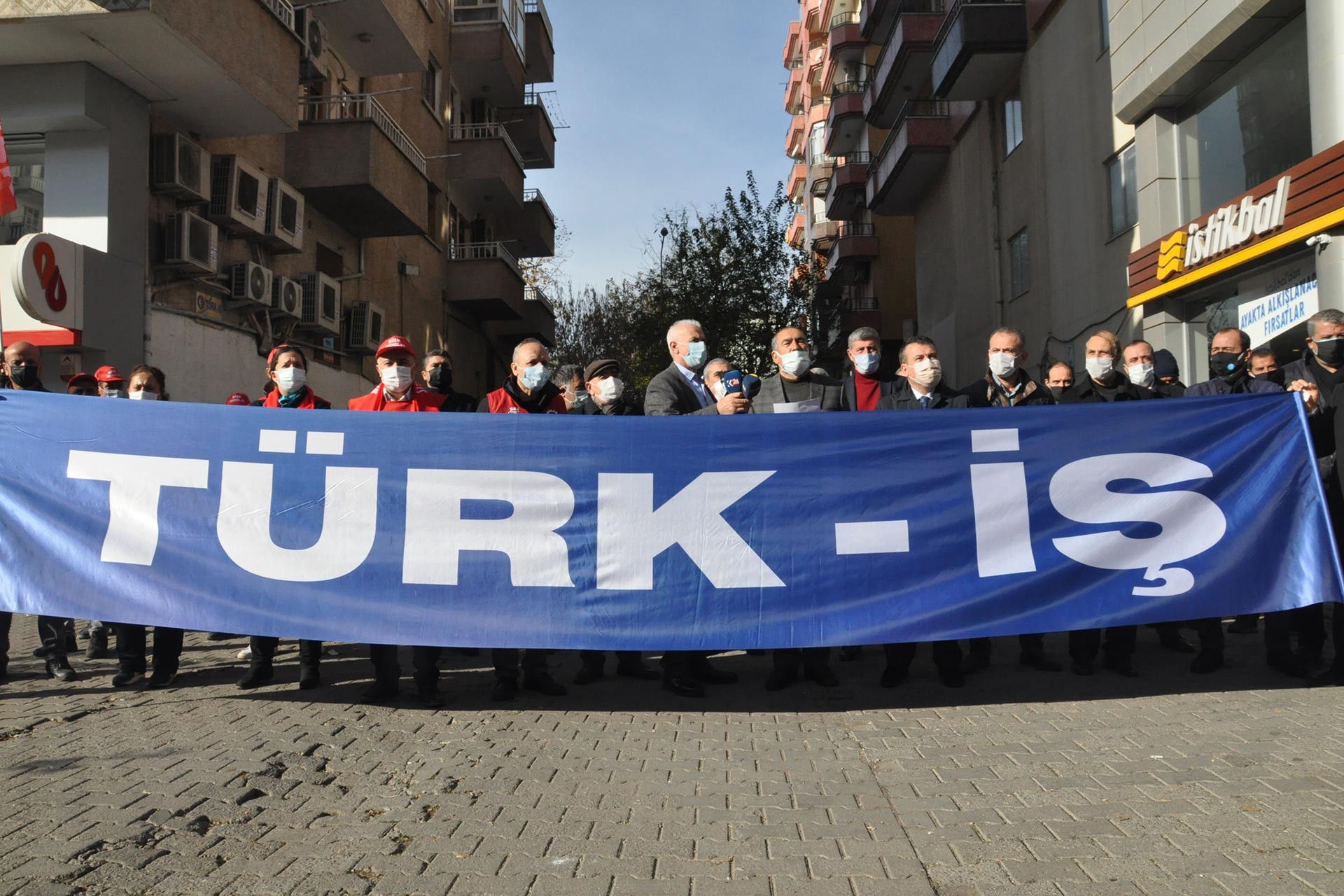 Türk-İş pankartı ve arkasında sendika yöneticileri