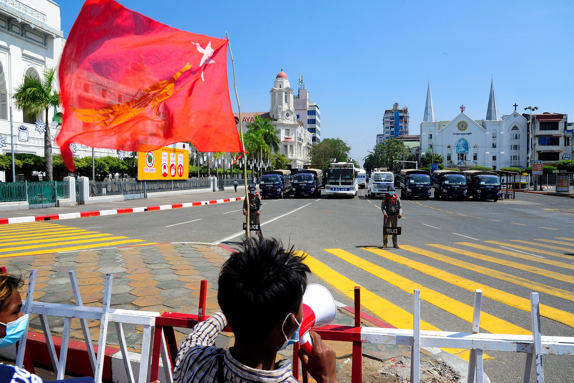 Myanmar'da askeri darbe karşıtı eyleme katılan bir genç (solda) askerlerin karşısında slogan atıyor