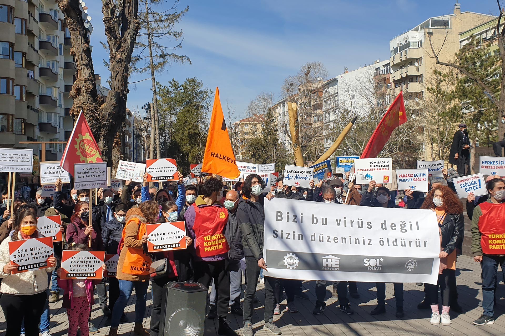 Bizi bu virüs değil sizin düzeniniz öldürür yazılı pankart ve arkasında eyleme katılanlar