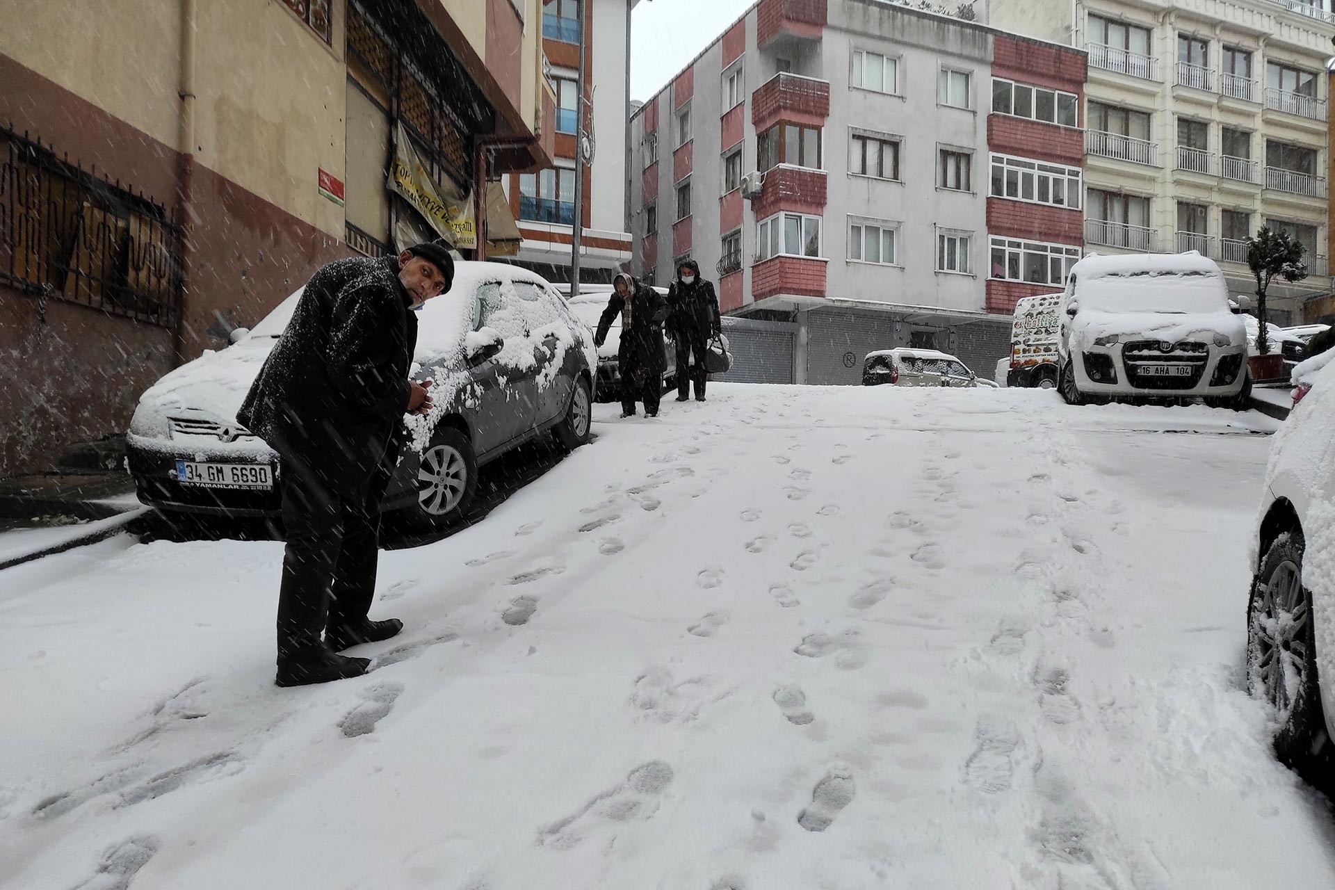 Karlı yokuşlu yolda yürümeye çalışan insanlar