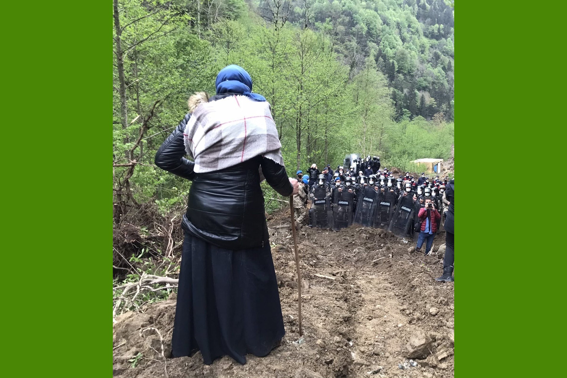 ikizderede bir kadın tepelik bir yerde değneğine yaslanarak aşağıdaki jandarmaya bakıyor. 