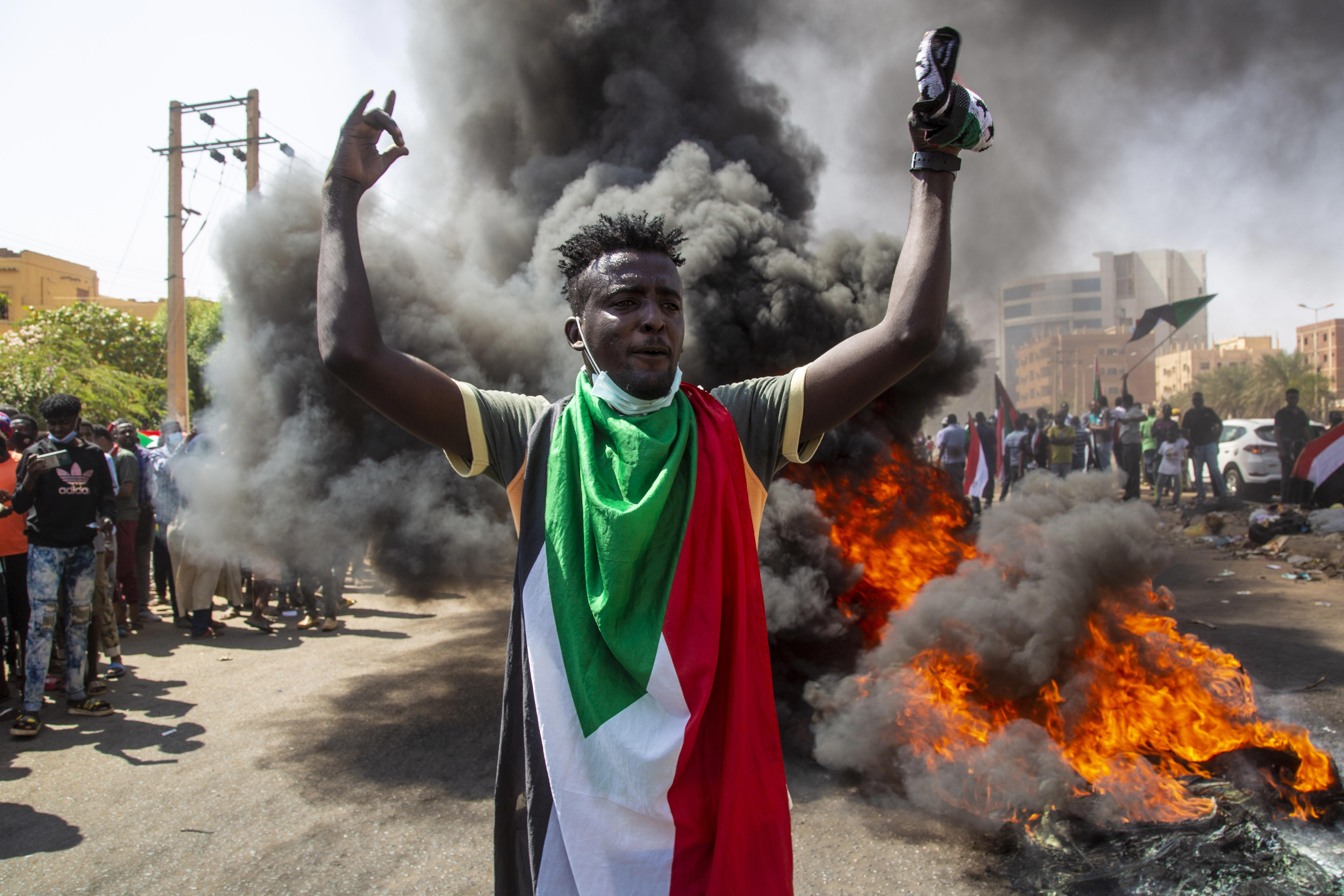 Göstericiler arasında üzerinde Sudan bayrağı bulunan bir kişi.