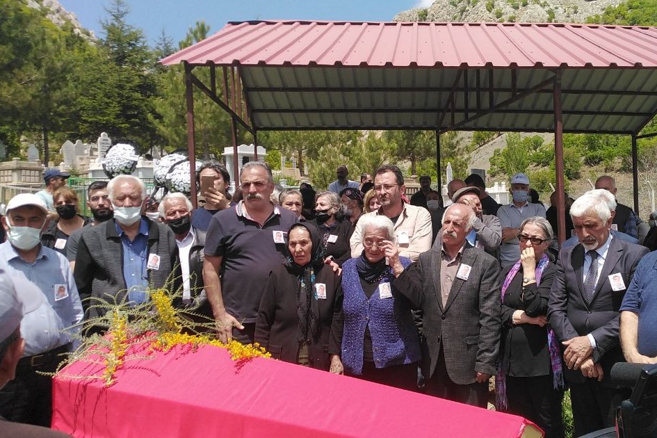 cenaze fotoğrafı, kızıl bayrağa sarılı tabut ve arkasında toplanmış insanlar