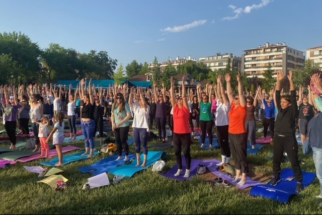 yoga yapan yüzlerce kadın ellerini havaya kaldırmış