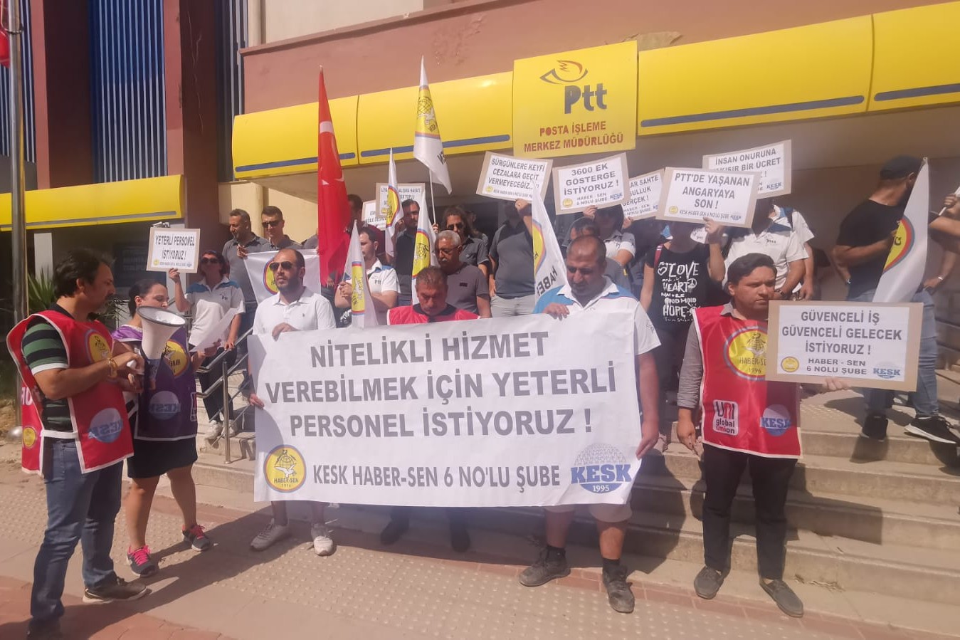 elinde döviz ve pankart olan insanlar PTT önünde açıklama yapıyor