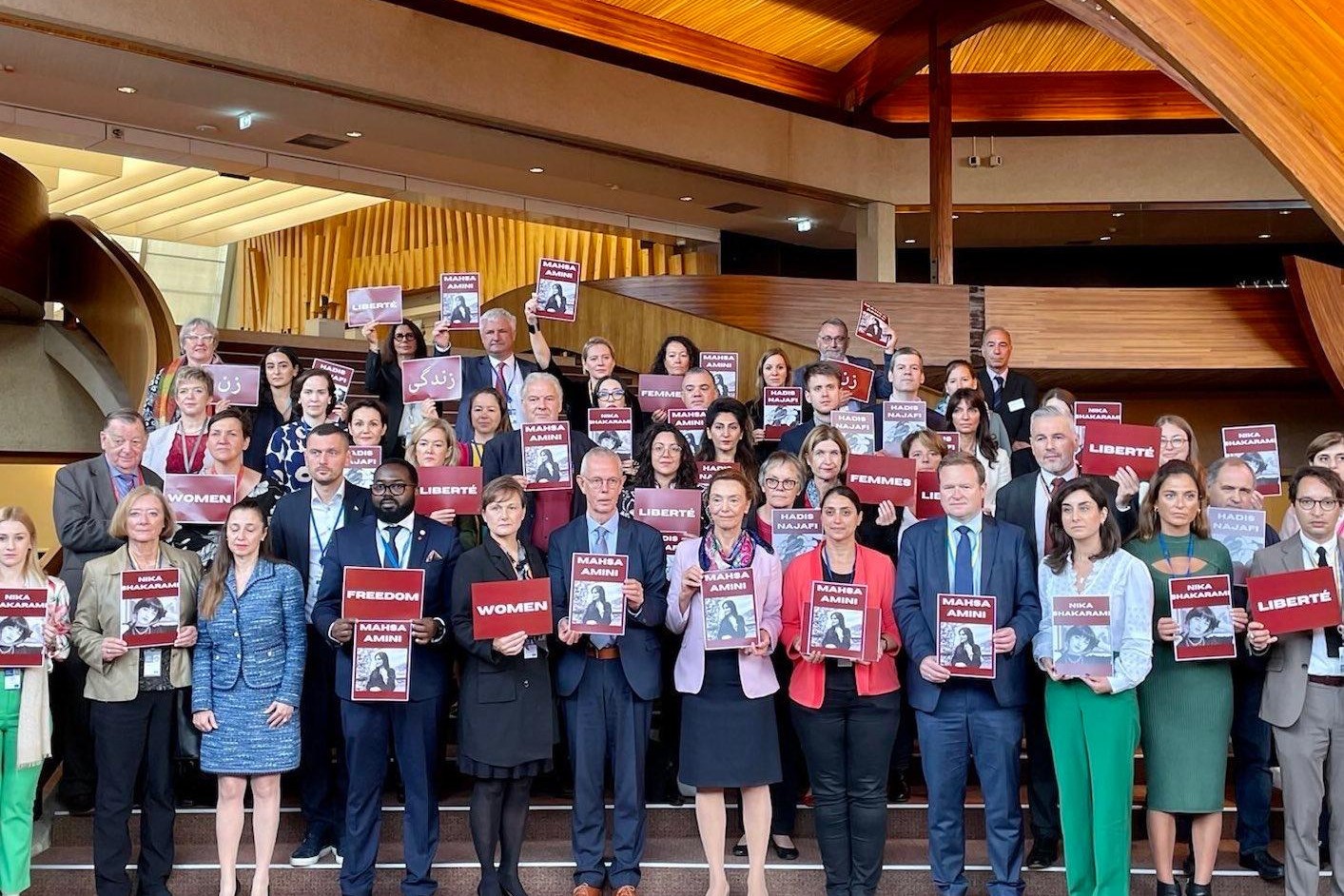 Ellerinde İran'da öldürülen kadınların fotoğraflarını taşıyan komisyon üyeleri