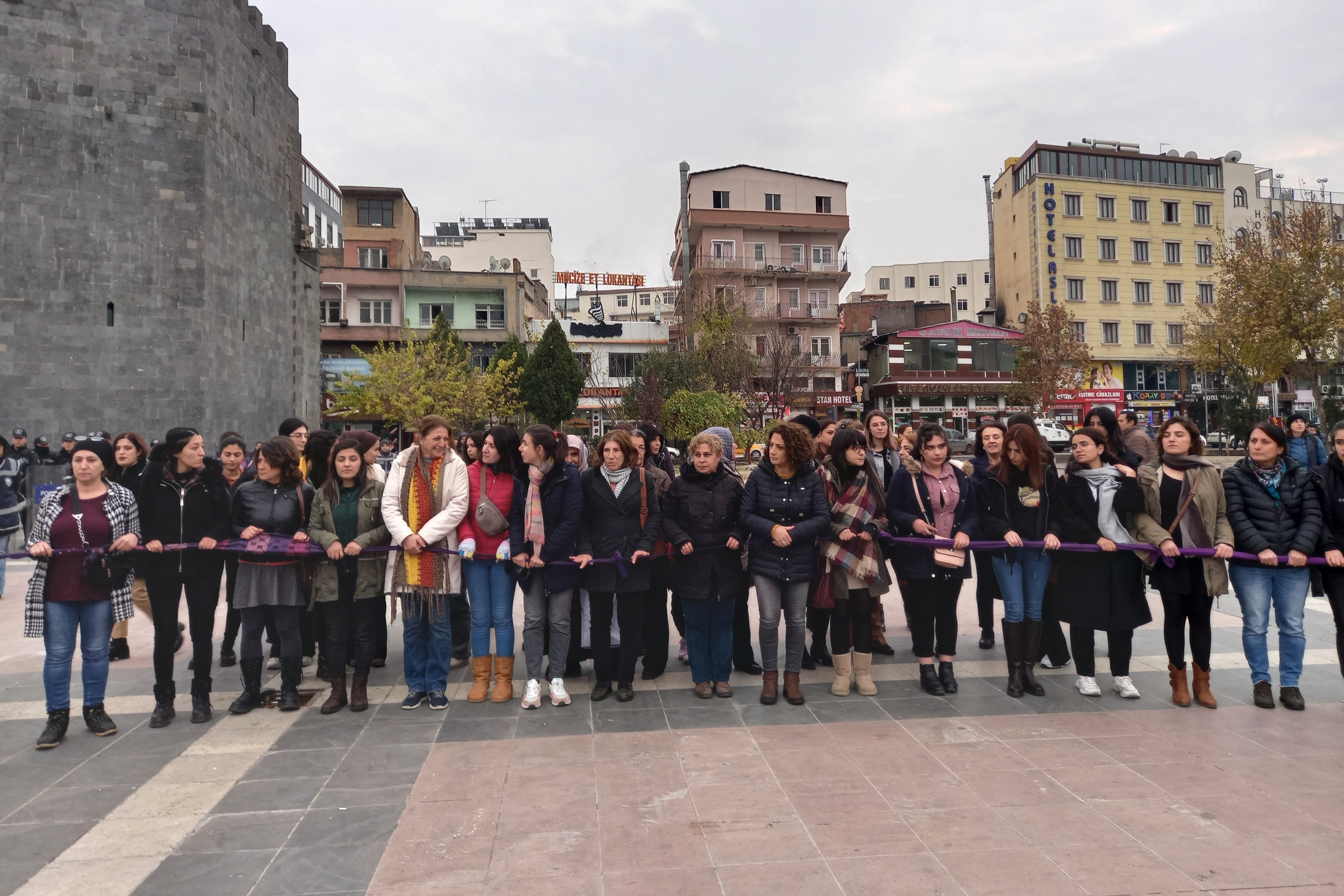 Kadınlar ellerinde tutukları mor renkli kumaş ile yan yana zincir oluşturuyor