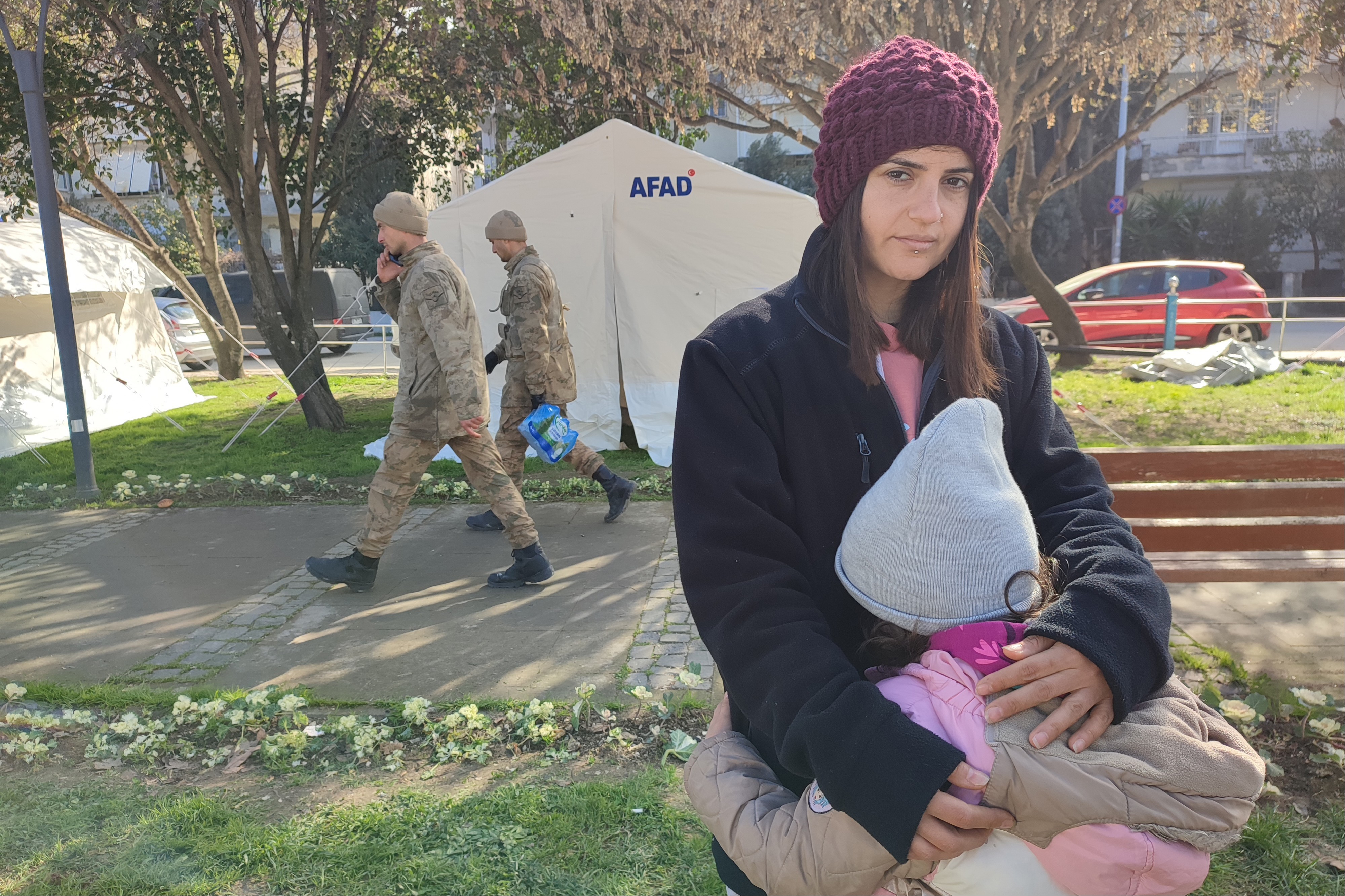 Hatay'da deprem çadırı önünde annesine sarılan bir çocuk