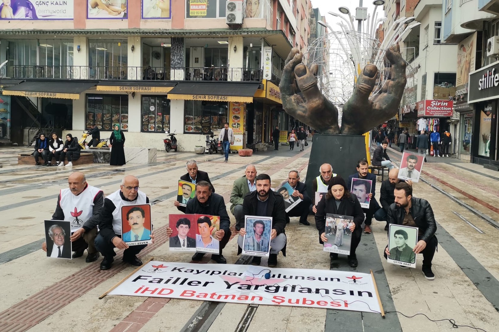 kaybolan yakınlarının fotoğraflarını taşıyan insanlar