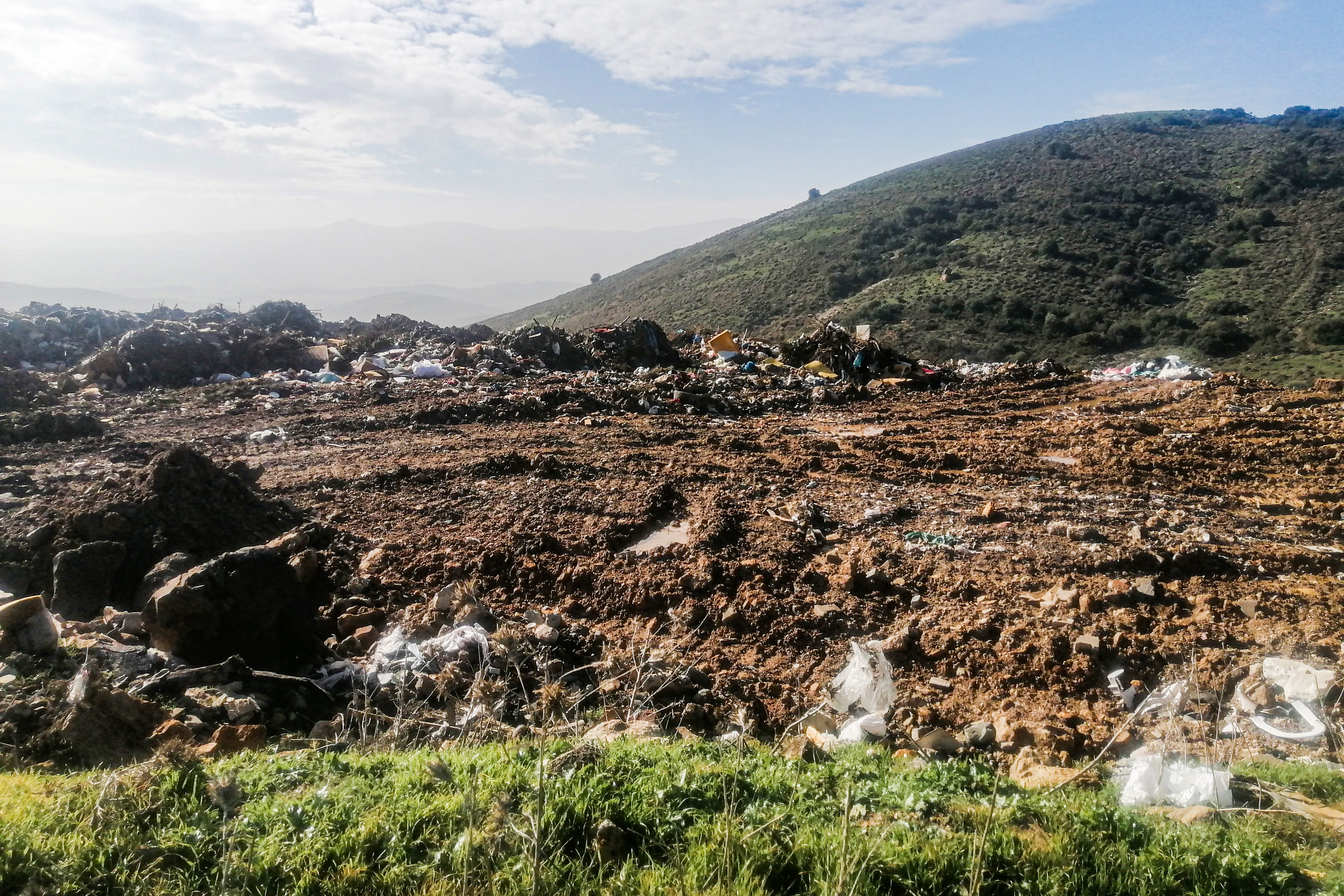 Sağ tarafı ormanlık bir yolda sarı bir harfiyat kamyonunun arkasındaki yolu sökmüş şekildeki fotoğrafı