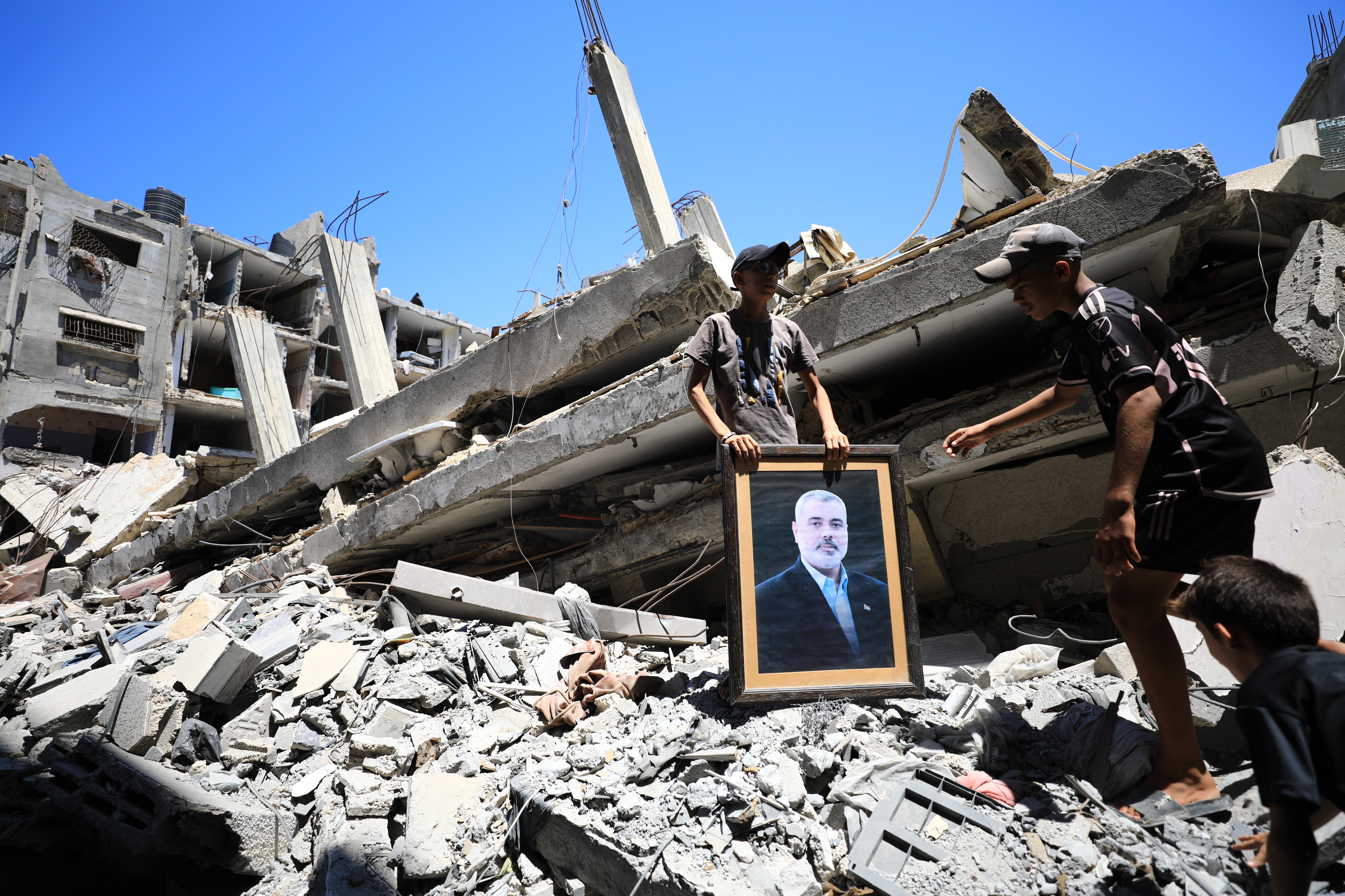 Gazze'de bir binanın enkazında Haniye'nin fotoğrafını taşıyan iki genç