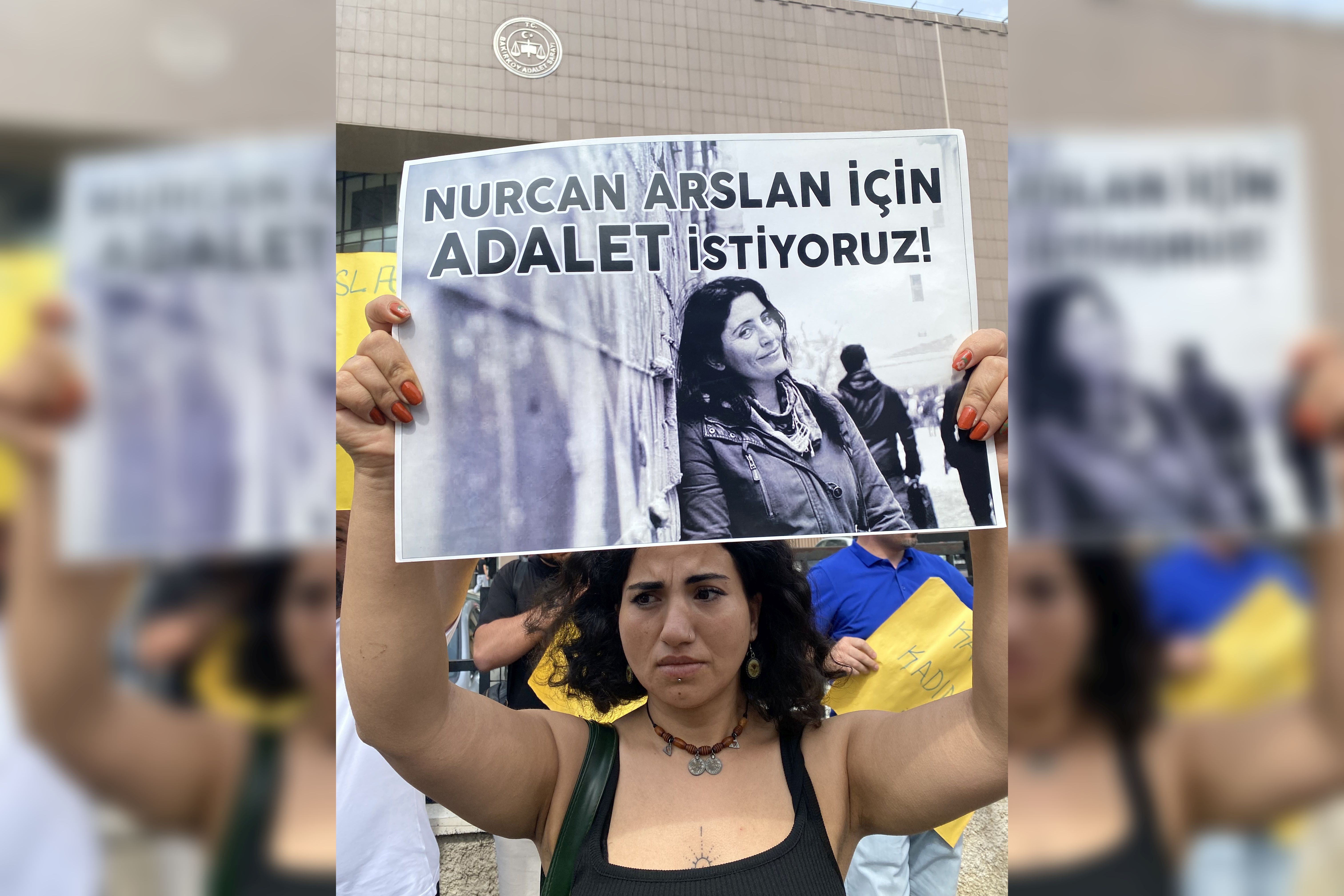 Nurcan Arslan için adalet istiyoruz yazılı pankart tutan kadın.