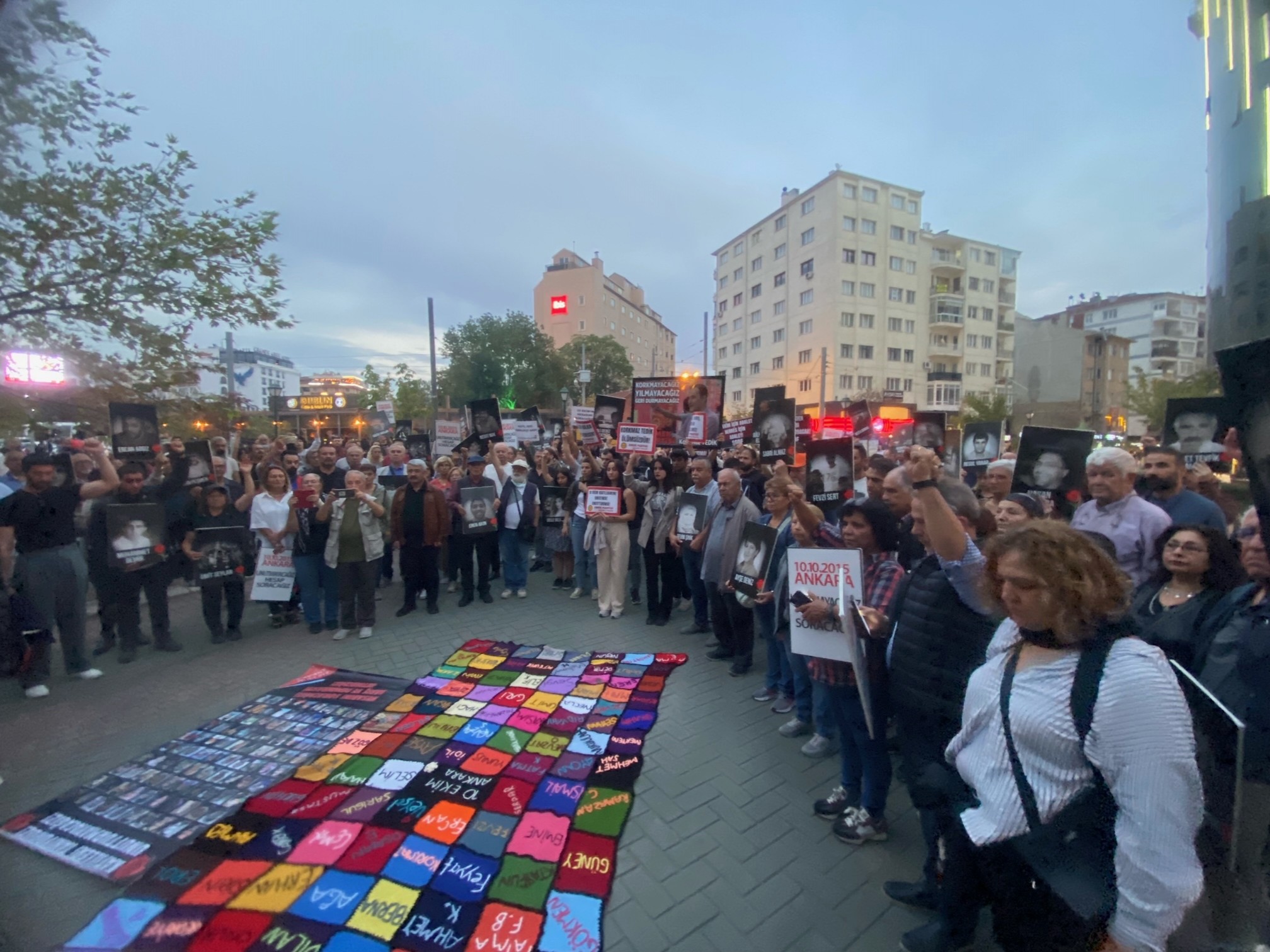 ellerinde fotoğraf ve slogan yazılı karton taşıyan insanlar