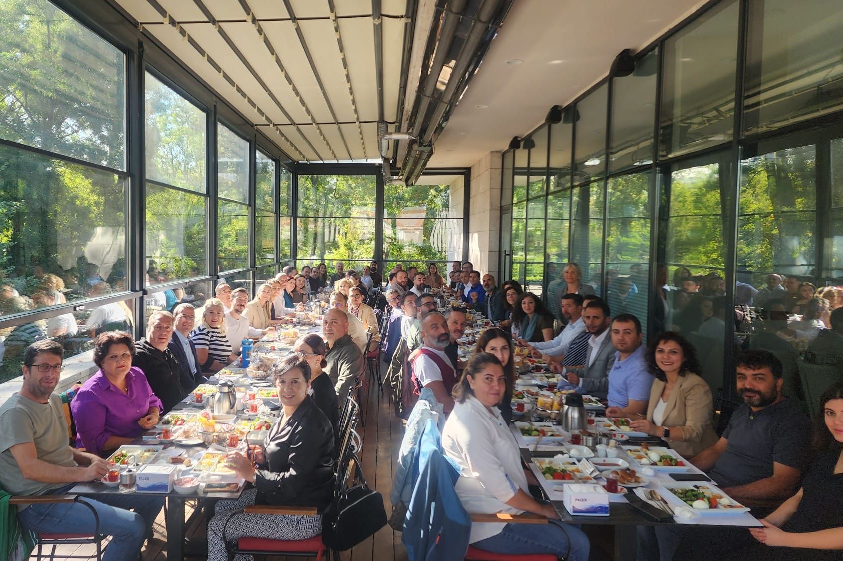 birbirine paralel iki uzun kahvaltı masasına oturan kalabalık